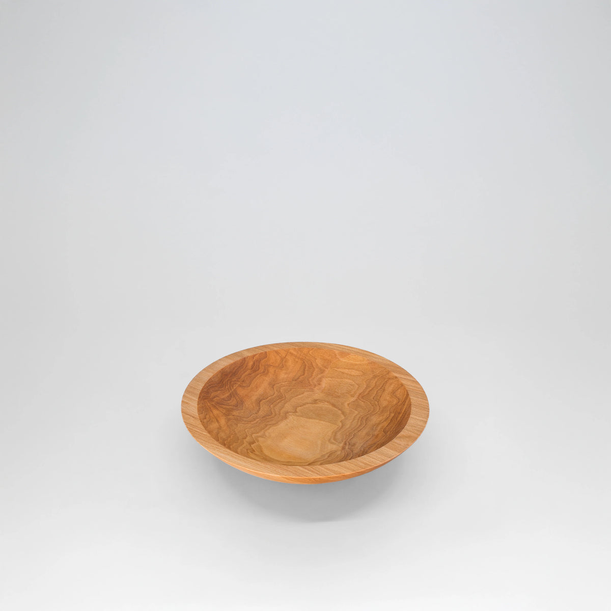 A 9" round cherry wooden bowl with a warm honey-brown color and natural swirling wood grain, engraved with trees and doves shown on a light gray background.