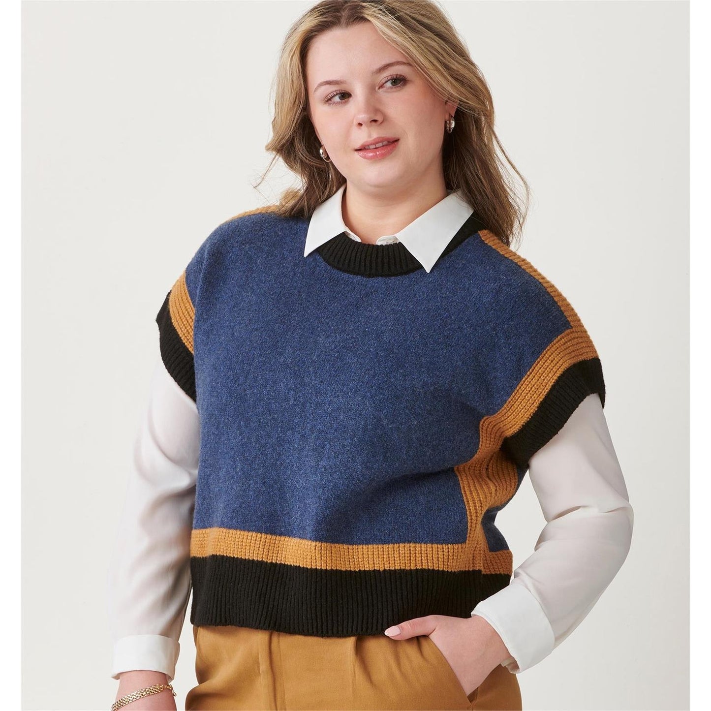 Woman wearing a blue, mustard, and black Charlie Paige Sweater Vest, Blue Melange over a white shirt on a plain background