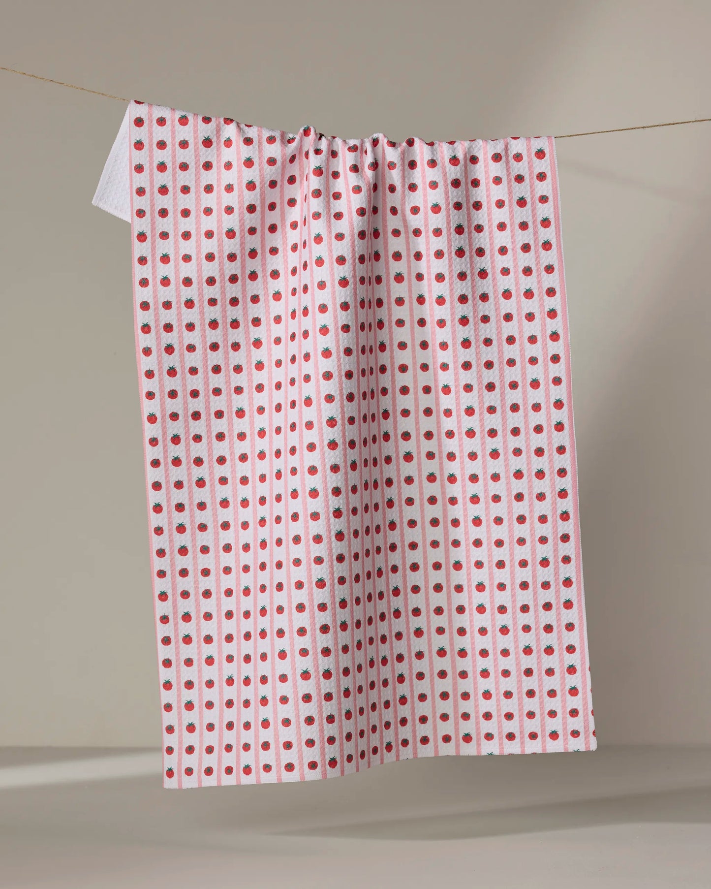 Highly absorbent and quick drying kitchen tea towel by Geometry made with Geoweave featuring the Tomato Stripes print with pink stripes and columns of red tomatoes.