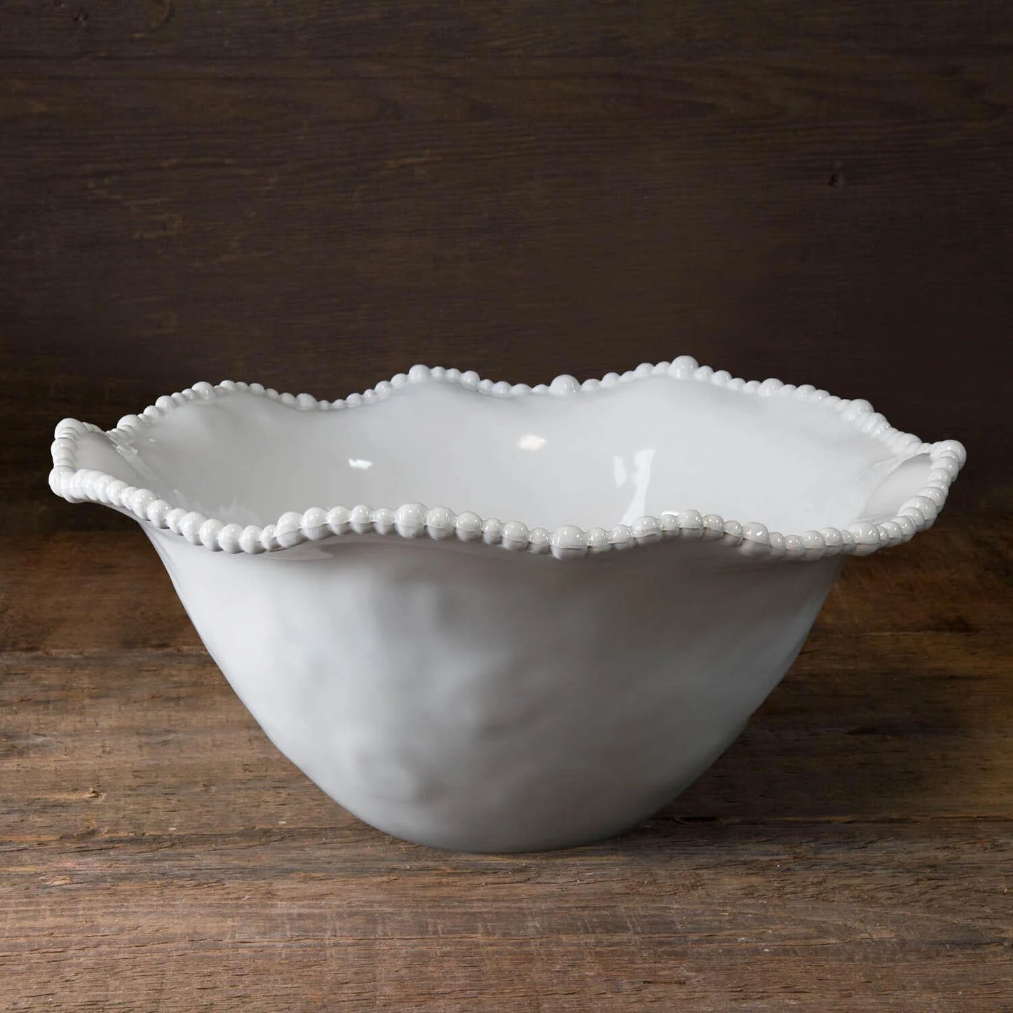 A white, melamine bowl with a pearl rim design on a wavy edge.