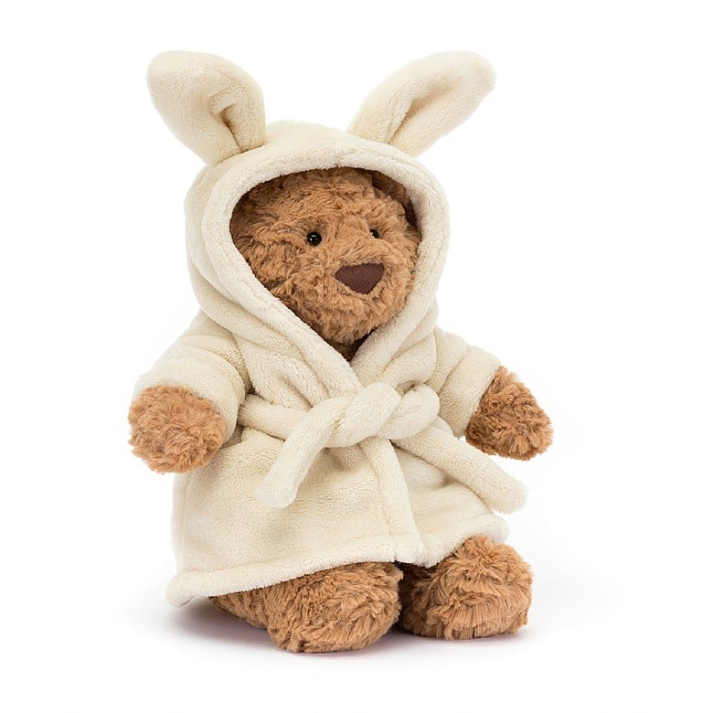 A plush bear wearing a beige bathrobe with bunny ears.