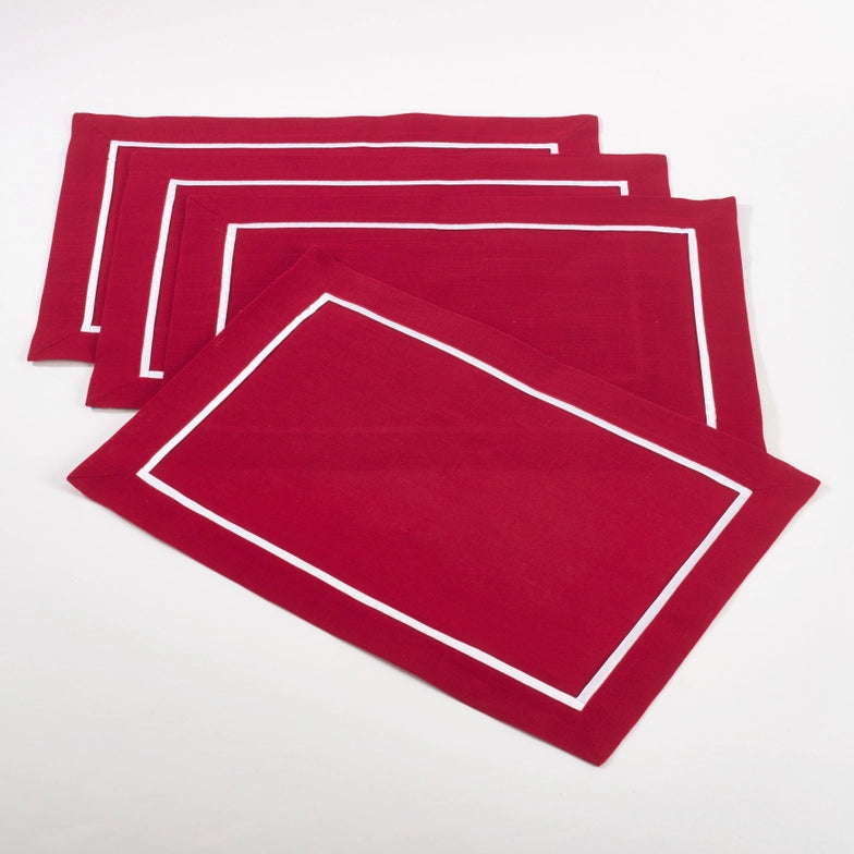 A set of red pleated placemats with a white border on a white background.