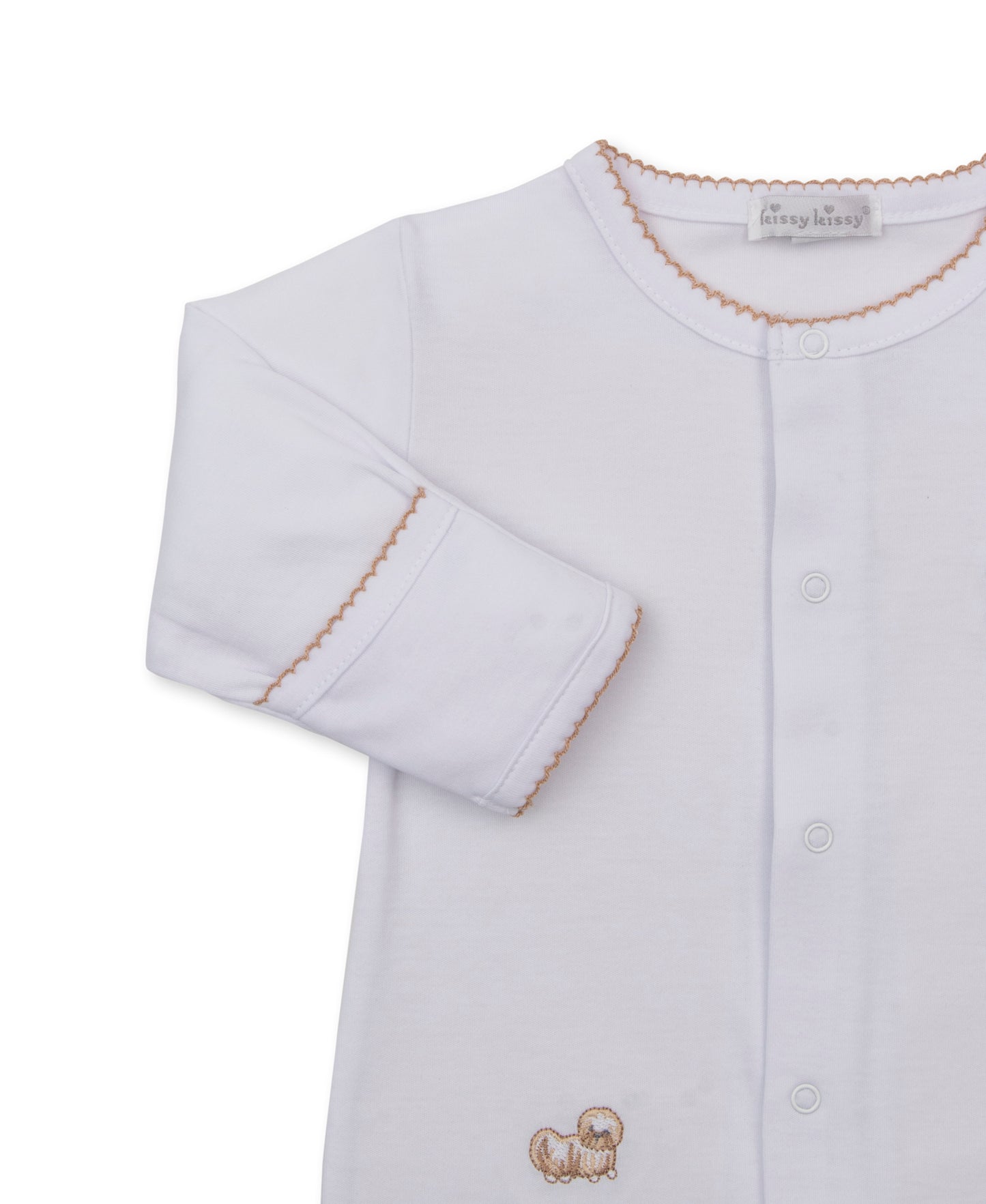 A white long-sleeve baby footie with a button-front closure, scalloped beige trim around the collar and cuffs, and a small beige embroidered puppy motif near the lower front.