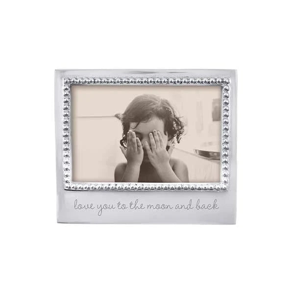 A beaded silver photo frame with the inscription 'love you to the moon and back' on the bottom.