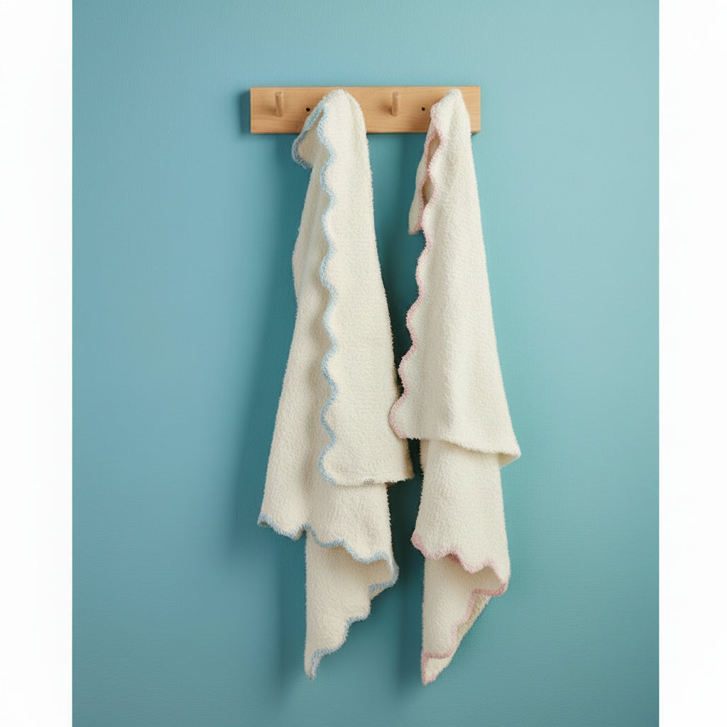 Two white towels with ruffled edges of blue and pink hanging on a wooden towel rack against a blue wall.