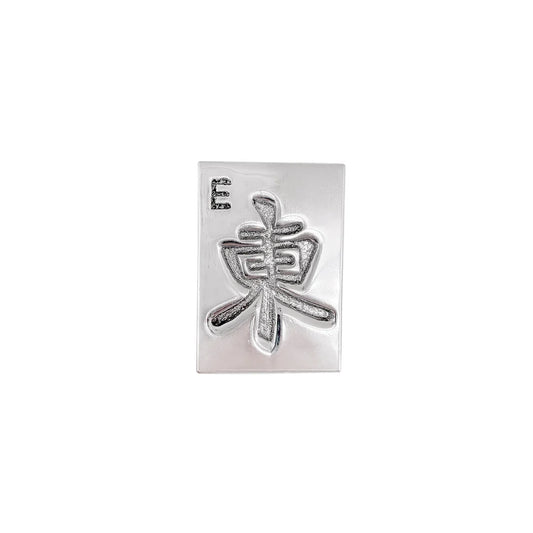 silver napkin weight featuring a mahjong tile design of East
