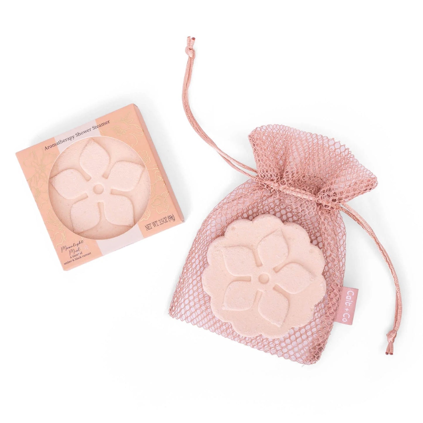 Peach flower-shaped shower steamer in a mesh bag with packaging with text amber and black currant