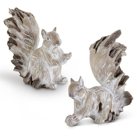 Two squirrel figurines with a weathered finish one is sitting and the other is crouching and holding an acorn