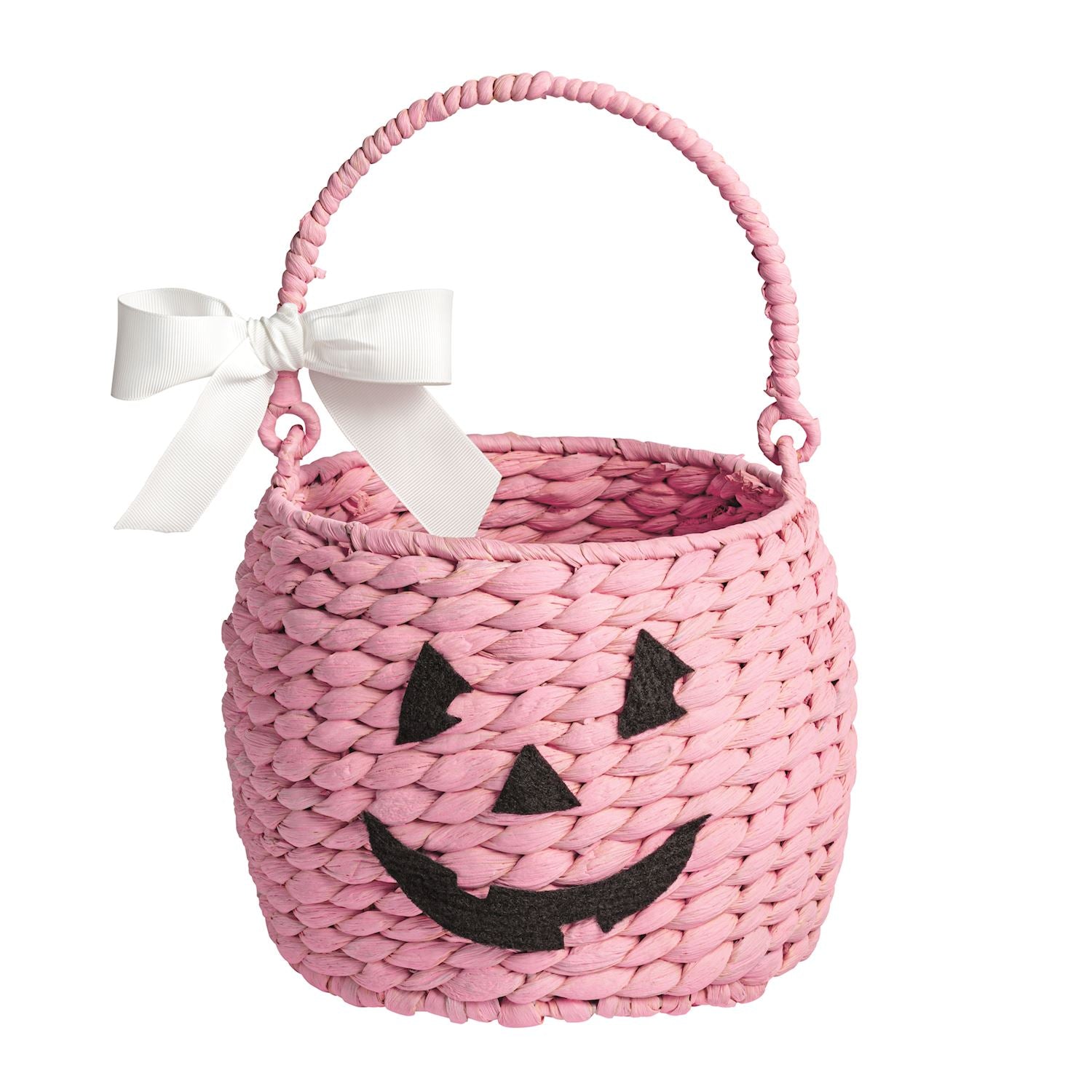 A pink woven straw Halloween trick-or-treat basket with a white bow on the side and a black jack-o'-lantern face, shown on a plain white background.