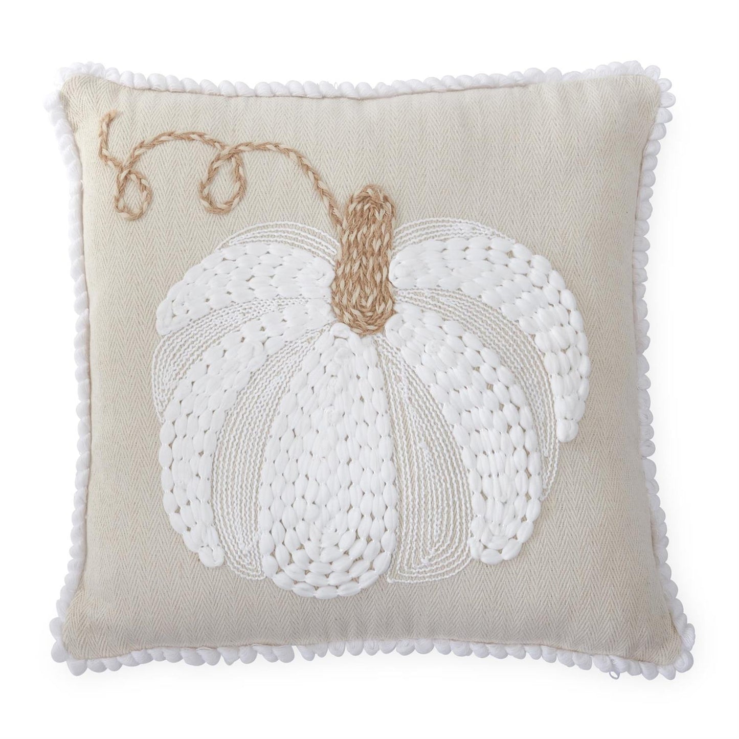 A square beige throw pillow with a white knitted pumpkin design and a tan stem, finished with a white pom-pom border.
