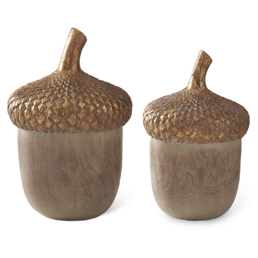 Two decorative acorn-shaped objects with textured metallic gold caps and a matte taupe-brown body, shown on a plain white background.
