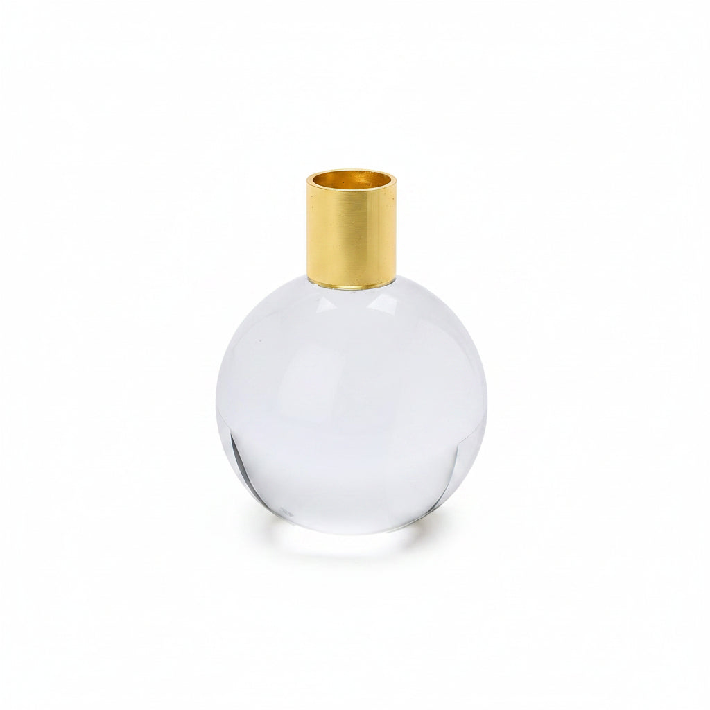 A round clear glass candleholder with a gold metal top