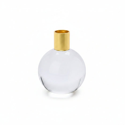A round clear glass candleholder with a gold metal top