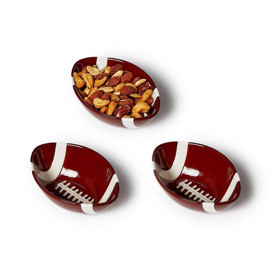 Three ceramic football-shaped bowls, one filled with nuts 