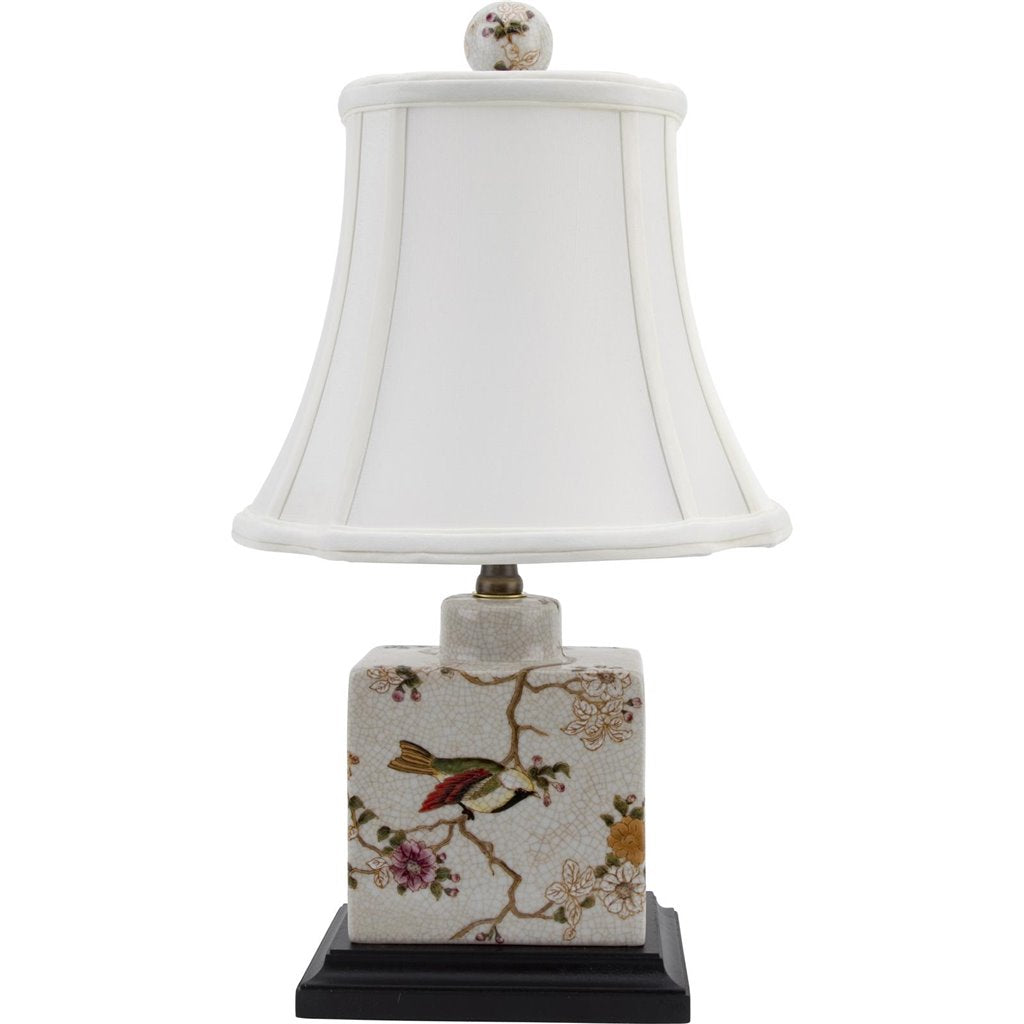 A porcelain lamp with a wooden base, featuring a floral pattern and a white bell-shaped lampshade.