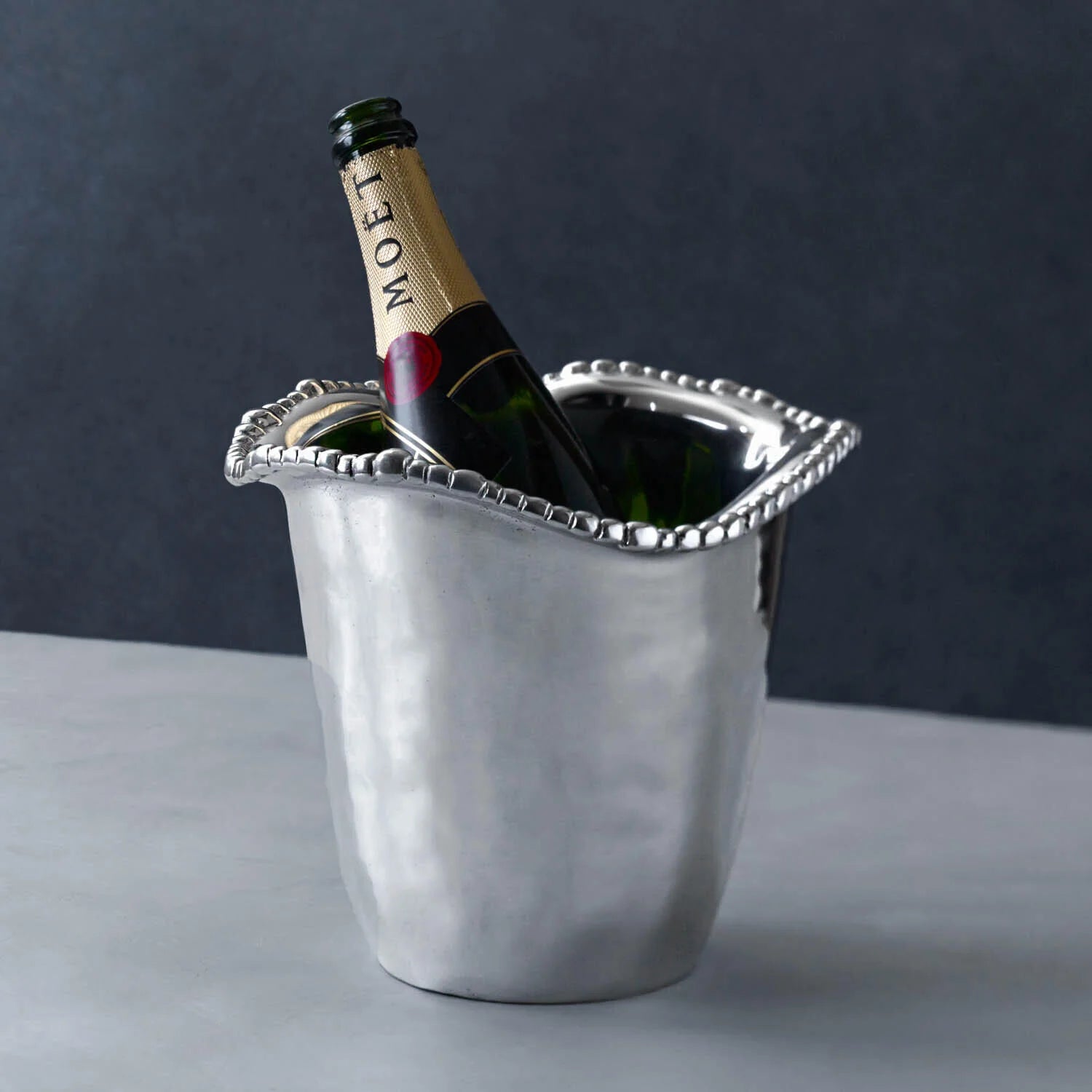 Silver ice bucket with a pearled rim and bottle of champagne 
