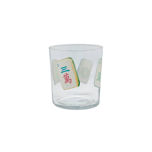 A clear glass tumbler featuring printed Mahjong tile graphics on the front, set against a plain white background.