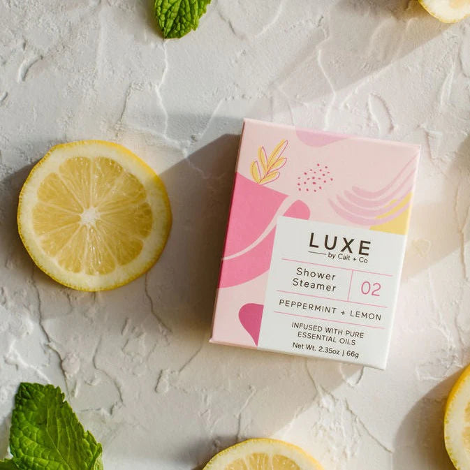A shower steamer with a peppermint lemon scent, placed on a surface with lemon slices and mint leaves around it, indicating freshness and the natural ingredients of the product.