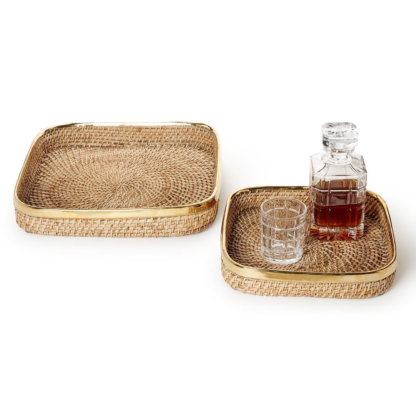 Two woven trays with a brass rim with a glass and decanter on a white background