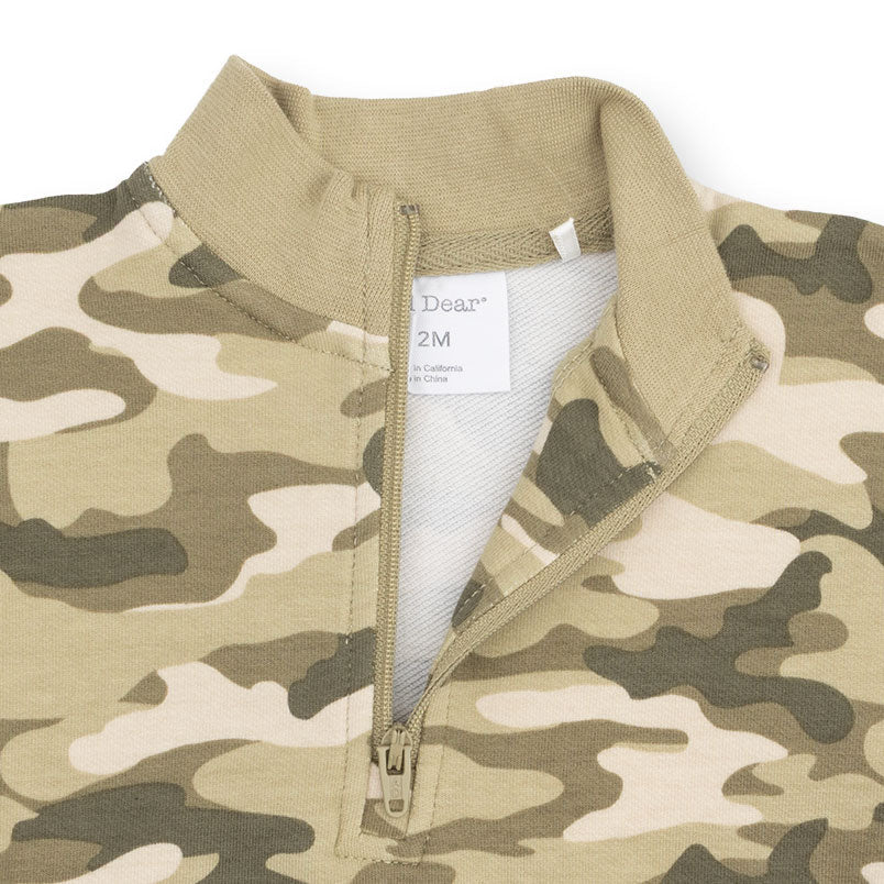 A close-up of an angel dear quarter-zip pullover with a camouflage pattern in beige, olive green, and brown, featuring a ribbed collar and a white inner neck label that reads 'Dear 2M'.