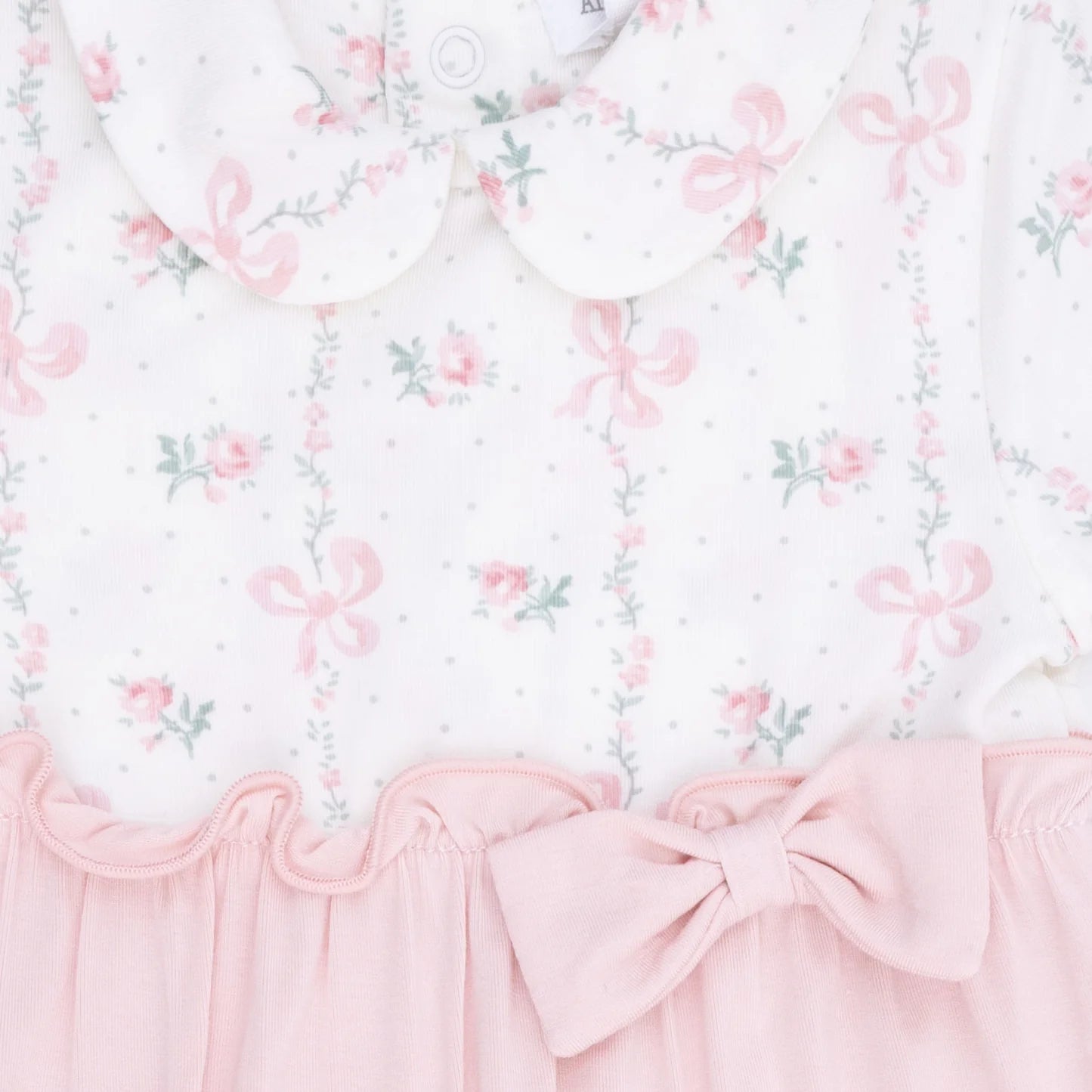 Close up view of an Angel Dear Dainty Buds & Bows Footie Pink baby onesie with white floral and bow print top, light pink bottoms with a pink bow 