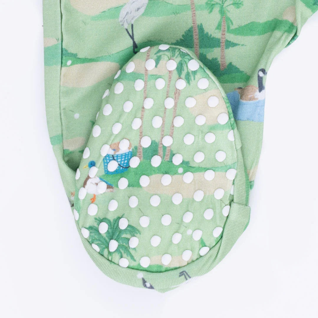 The rubber dots on the bottom of a foot on an An Angel Baby Golf Oasis Animals 2 Way Zipper light green Footie with a golf course design featuring playful animals that may be found on a golf course. 