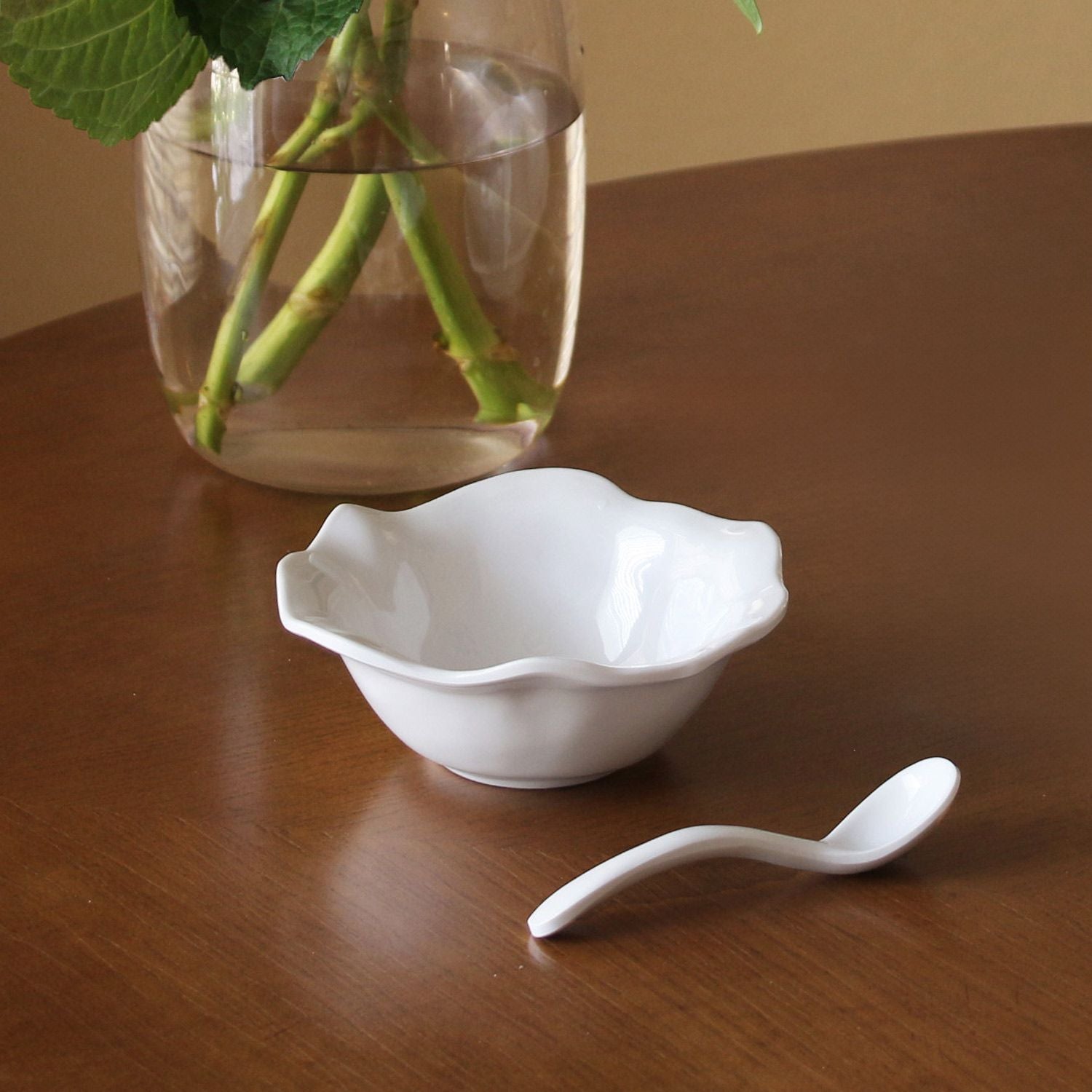 A small white melamine bowl with a matching spoon.