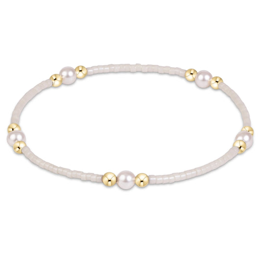 A delicate stretch enewton Hope Purpose Gold Milkshake  bracelet featuring a strand of tiny pale beads, accented with several large white pearls and polished gold spacer beads, shown on a clean white background.