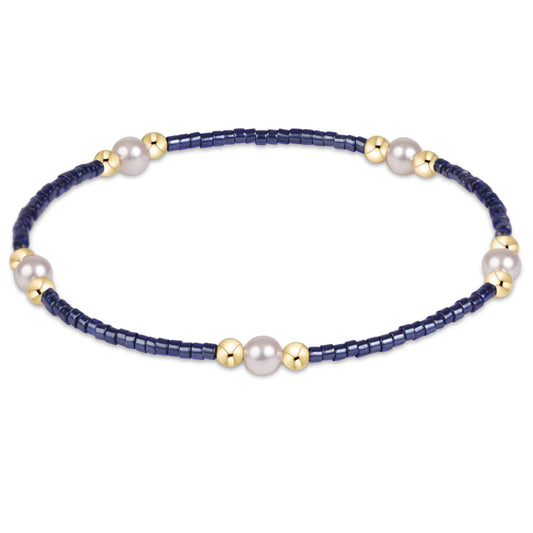 A beaded stretch enewton hope purpose pearl navy bracelet featuring dark navy blue faceted beads, white freshwater pearls, and polished gold spacer beads, shown on a clean white background.