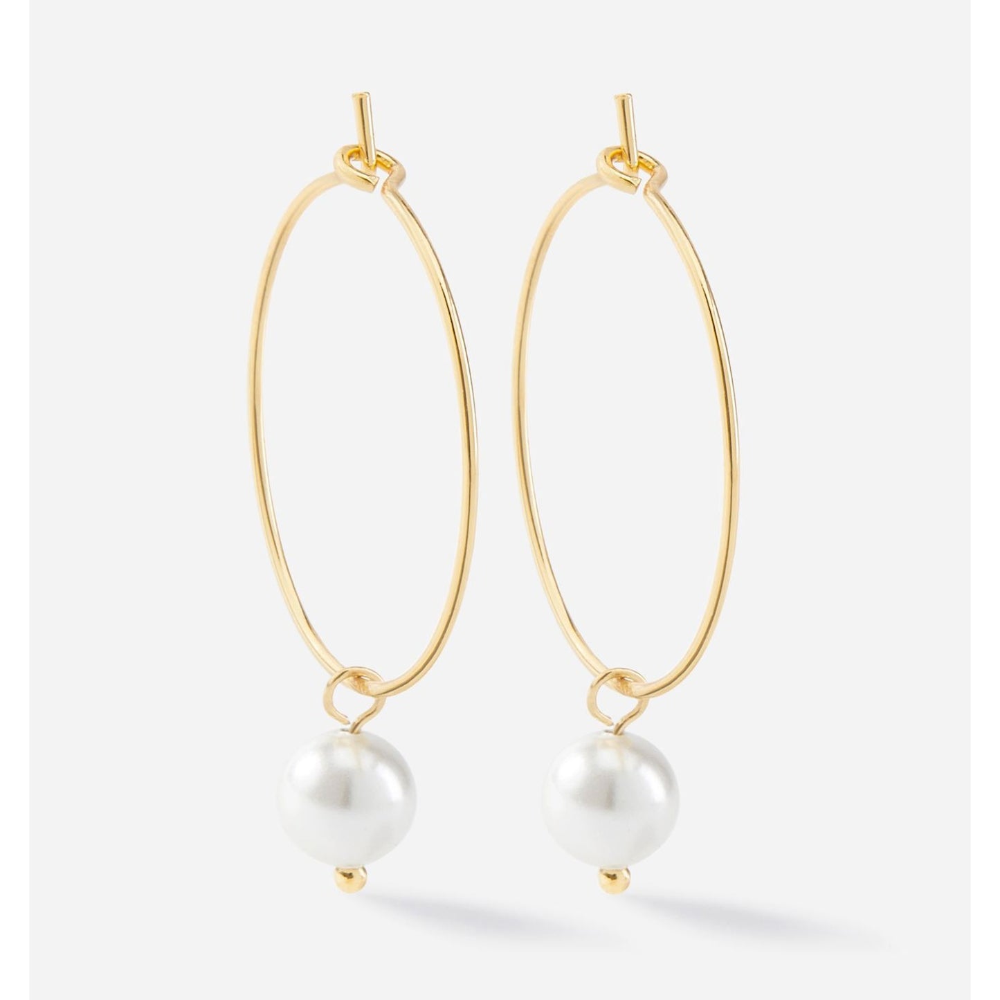 Charlie Paige Gold Drop Pearl Hoop Earrings with white pearls on a light gray background