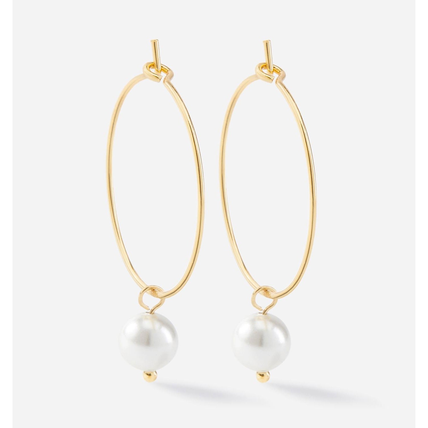 Charlie Paige Gold Drop Pearl Hoop Earrings with white pearls on a light gray background