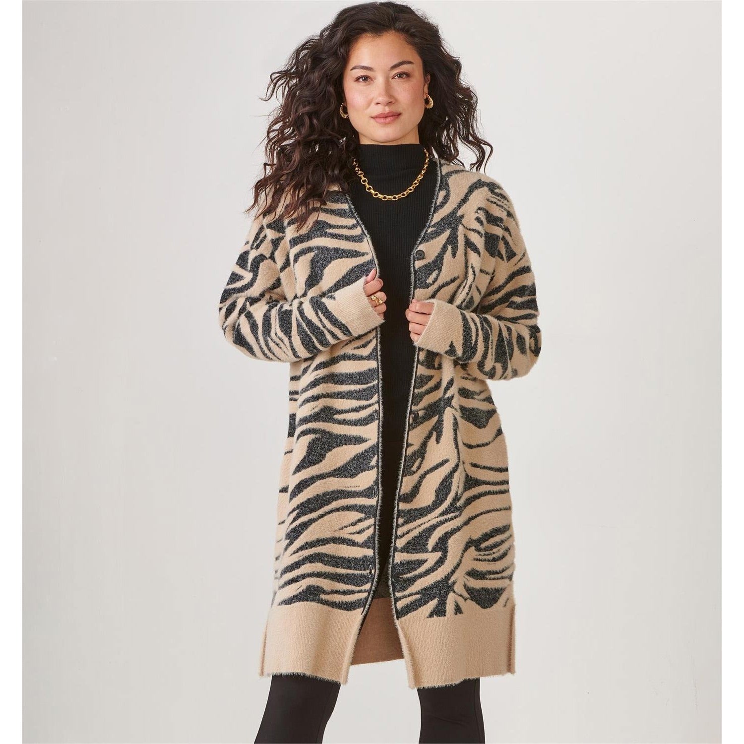 Woman wearing a long zebra print cardigan by Charlie Paige on a plain background