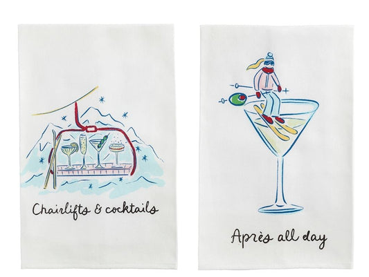 Two mudpie white kitchen towels  each printed with a different cocktail-themed illustration and humorous caption: 'Chairlift & cocktails,' 'Après all day,' 