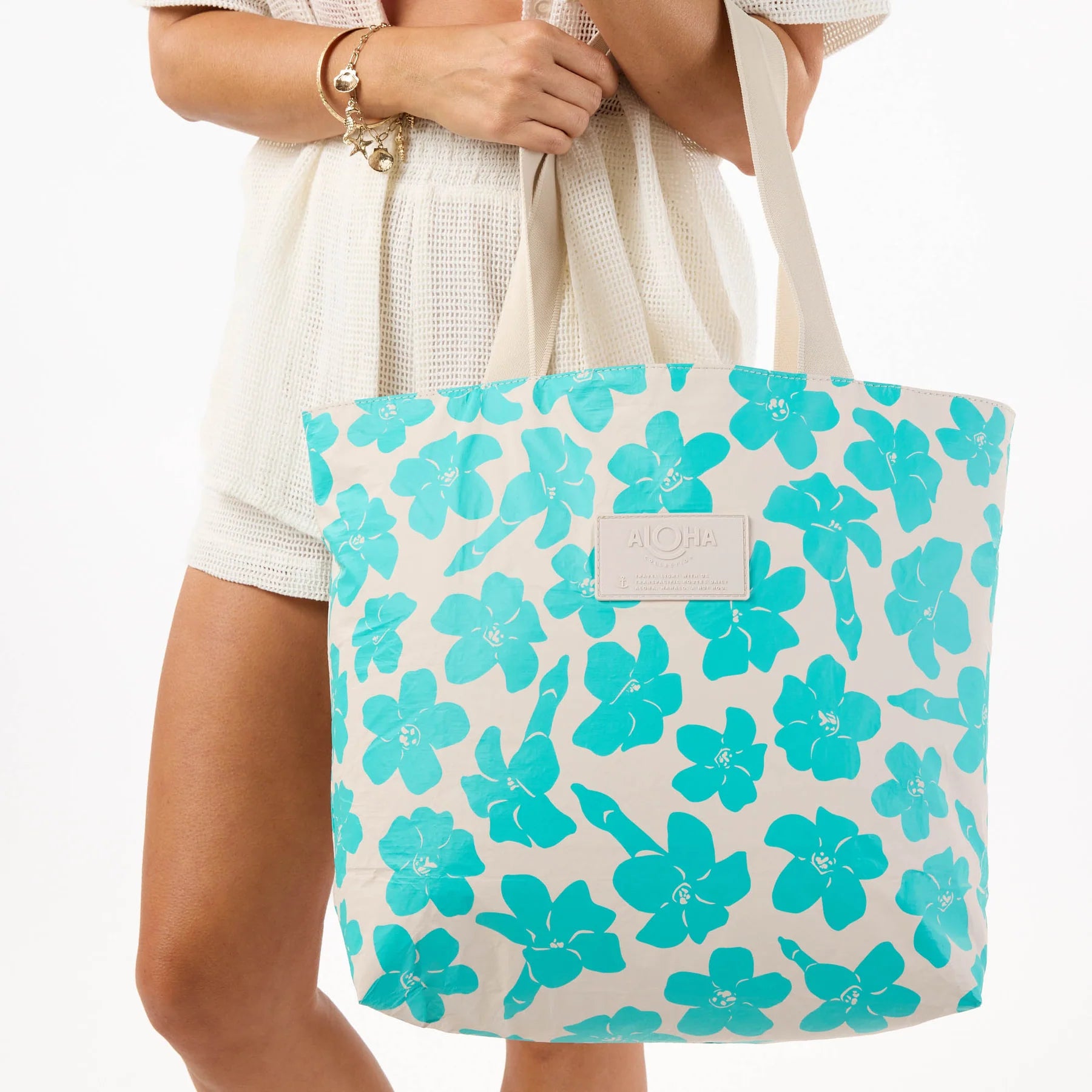 Aloha Tote bag with blue floral pattern held by a person on a white background