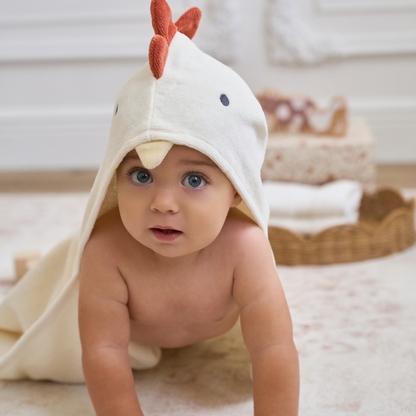Baby wearing an elegant baby chicken-themed hooded towel in a cozy room.
