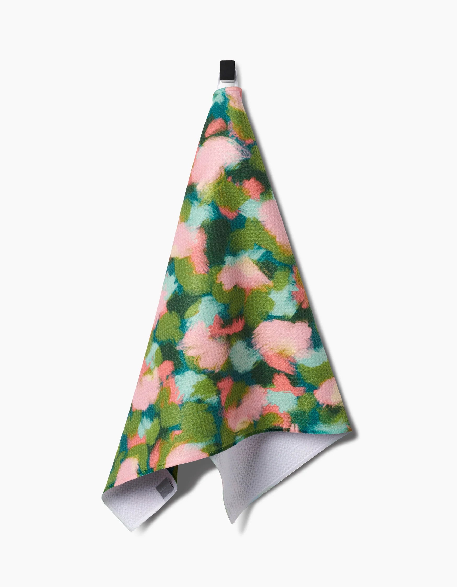 Geometry stroke of genius print tea towel with green, blue and pink colors hanging on a hook