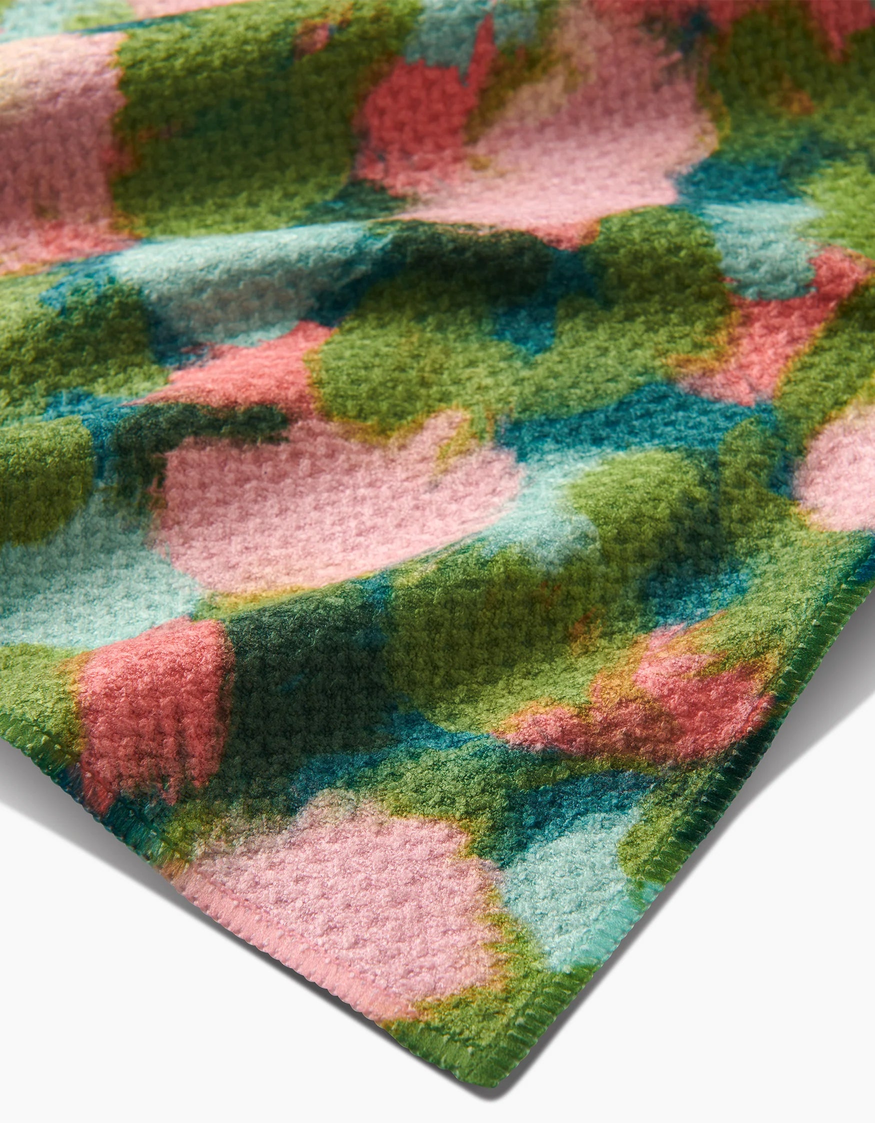Close-up of a Geometry teal towel Stroke of Genius multicolored textured fabric with pink, green, and blue patterns.