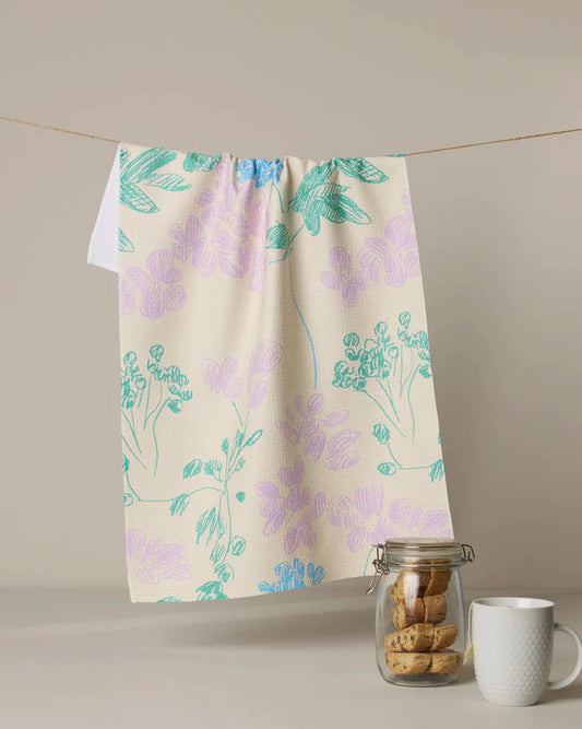 Geometry Julieta Floral patterned towel hanging on a line with cookies in a jar and a mug below.