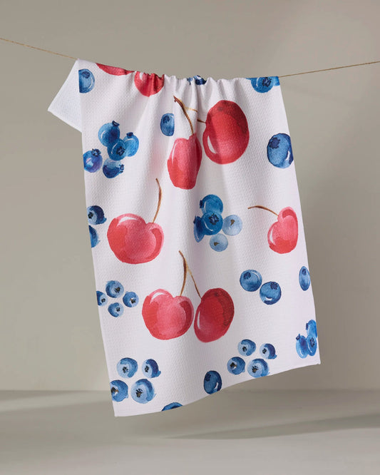 geometry=t Towel with red cherries and blueberries pattern hanging on a line.