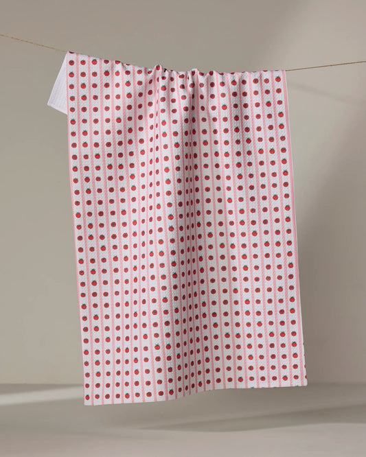 Highly absorbent and quick drying kitchen tea towel by Geometry made with Geoweave featuring the Tomato Stripes print with pink stripes and columns of red tomatoes.
