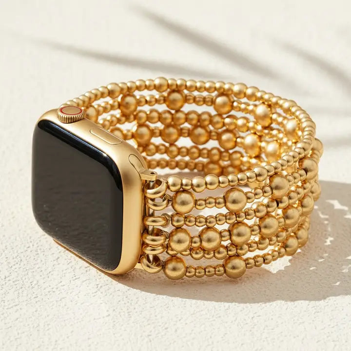 Golden demure stretch apple watch strap by cape diablo with a gold beaded band on a light background