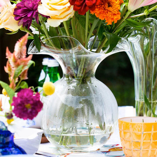 Clear glass fluted vase with flowers on a table outdoors