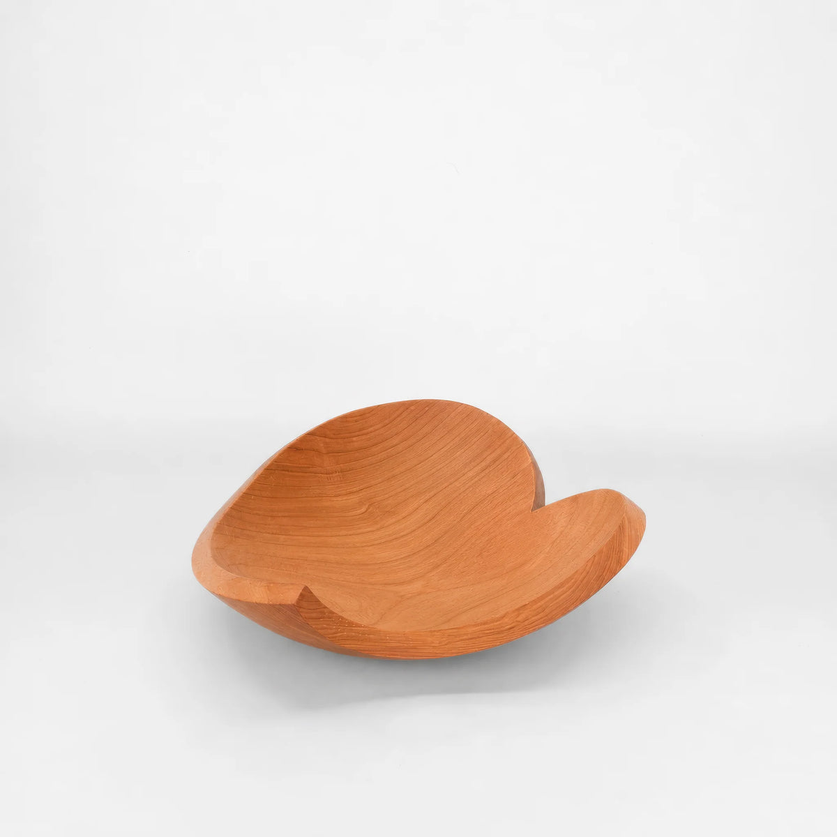 A Holland Bowl Mill teardrop heart shaped wooden bowl with a warm orange-brown finish in cherry wood , photographed on a seamless light gray studio background.  Engraved Forever and Always on the bottom