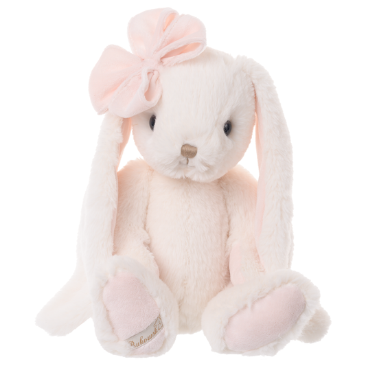 A soft plush bunny toy in very pale pink and white, with long floppy ears, a large pale pink bow on the head, black eyes, a small pink nose, and pale pink paw pads. A small fabric tag is visible near one paw.