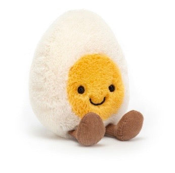 A plush toy shaped like a smiling fried egg, with a white fluffy shell, yellow yolk face, and brown feet, photographed on a clean white background.
