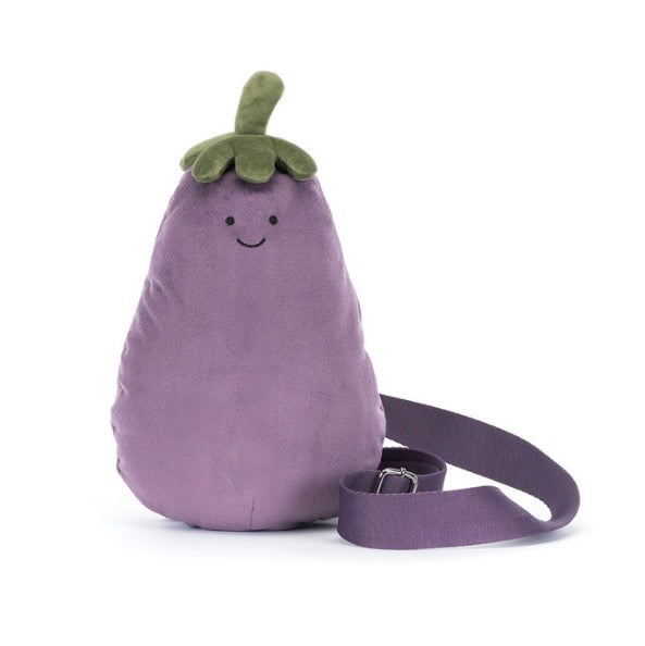A purple eggplant-shaped plush crossbody bag with a green stem and a smiling embroidered face, shown on a white background with its matching strap.