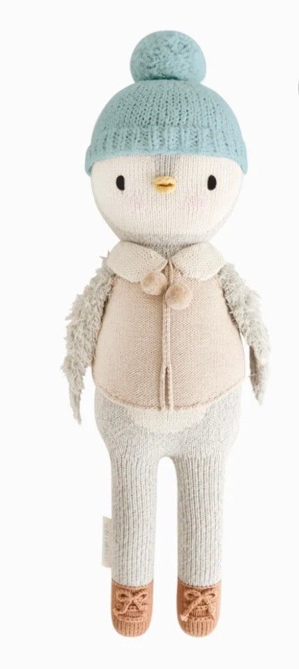 Knitted penguin wearing blue cap vest with a collar and pom poms 
