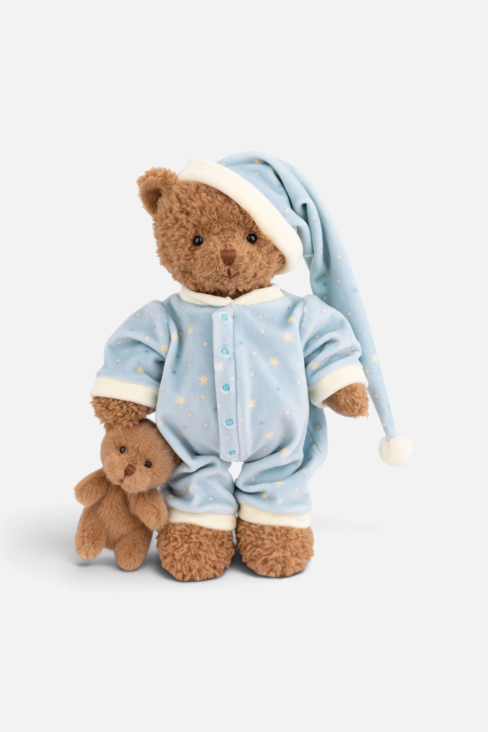 A plush teddy bear wearing light blue pajamas with small yellow star prints and a matching long nightcap, posed next to a smaller teddy bear on a clean white background.