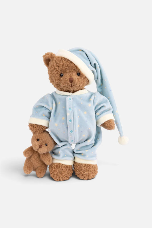 A plush teddy bear wearing light blue pajamas with small yellow star prints and a matching long nightcap, posed next to a smaller teddy bear on a clean white background.