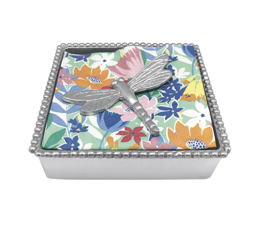 A silver dragonfly-shaped napkin weight.